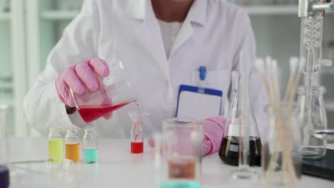 a person in a lab coat and gloves performing a chemical experiment in a laboratory