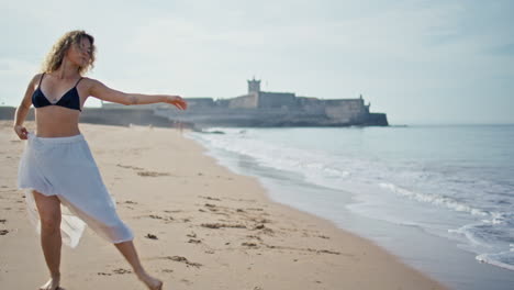 inspired girl moving body at sand beach in front coastal castle. woman dancing