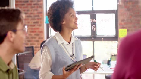 Happy-biracial-businesswoman-with-tablet-at-casual-meeting-with-diverse-colleagues,-slow-motion