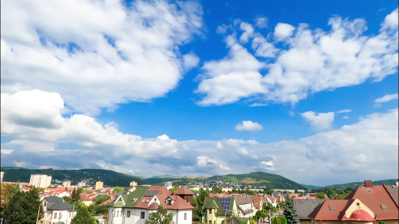White soft cumulus clouds floating above the city. Low angle view at the beautiful cloudscape transforming above the urban landscape. Timelapse.