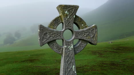 celtic cross in a misty green landscape