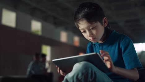 focused boy surfing internet using pad computer closeup. teen pupil sitting hall