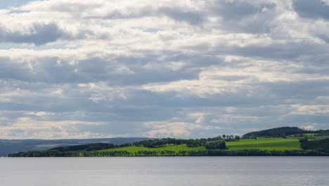 lapso de tiempo de nubes lentas sobre tierras de cultivo verdes y gran lago