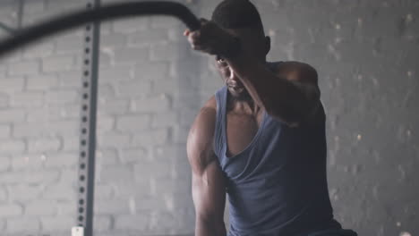 using battle ropes, muscular man exercising intensely in gym, focusing on workout