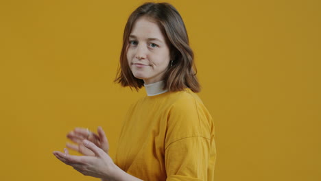 woman clapping against a yellow background