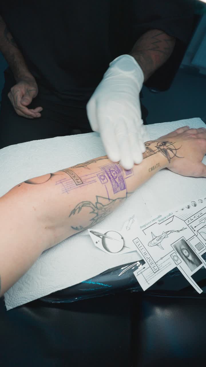 Vertical shot of artist clean fresh tattoo with napkin, remove excess ink