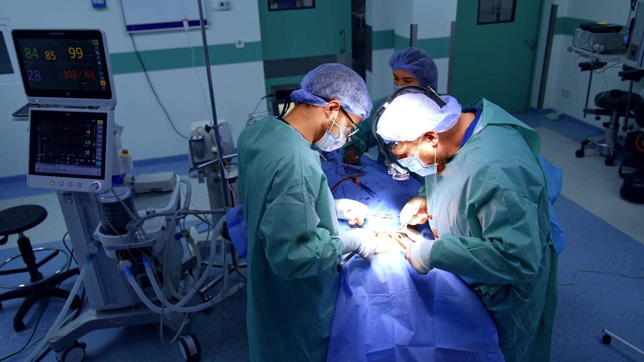 Una squadra composta da due chirurghi e un'infermiera lavora in sala operatoria. Chirurghi professionisti eseguono un intervento maxillo-facciale. Vista dall'alto.