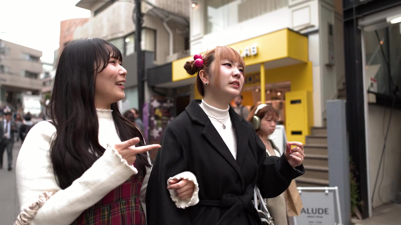 Dos amigos con estilo hablan y gesticulan mientras caminan por la calle Takeshita de Harajuku en Tokio, Japón