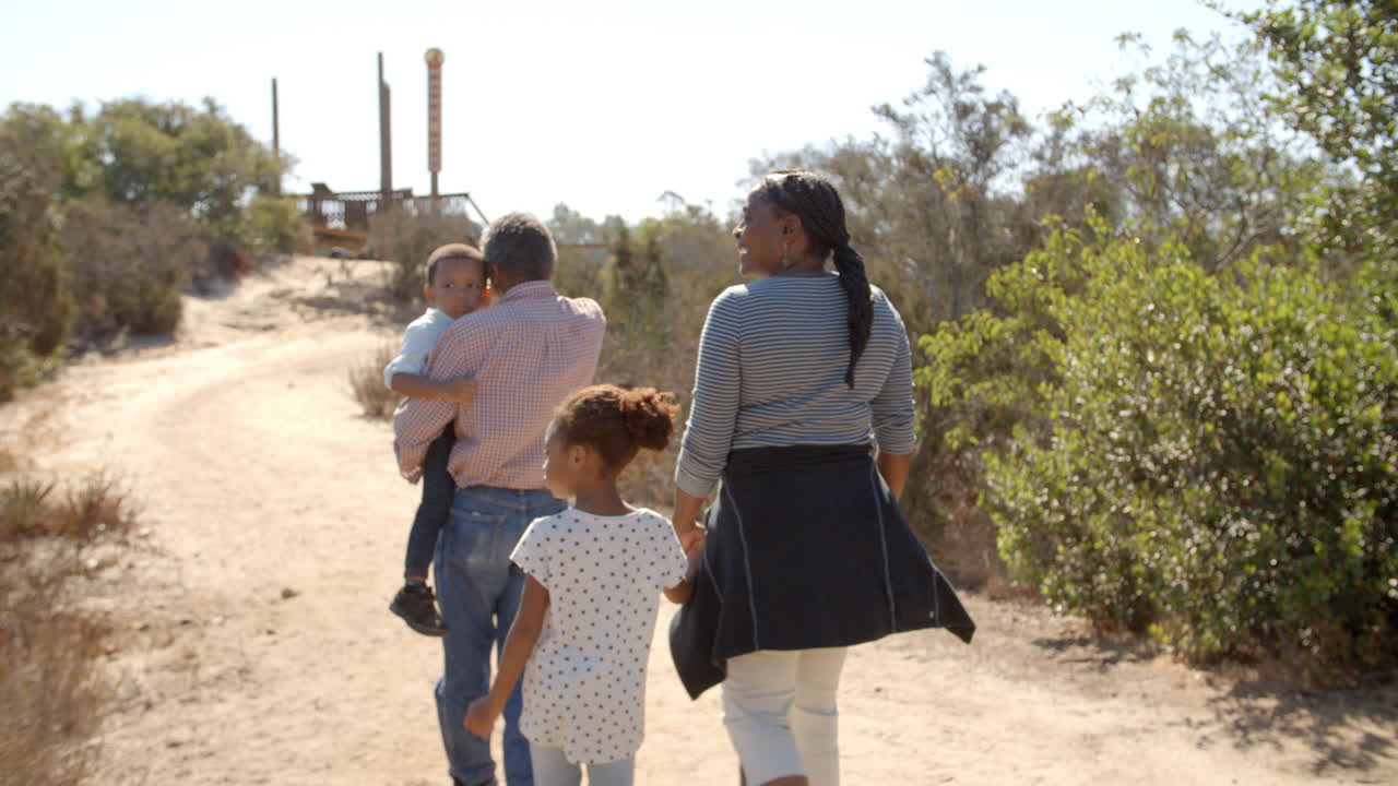 abuelos y nietos negros caminan por el camino, vista de atrás