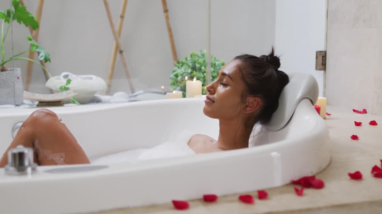 집에서 목욕탕에 누워 있는 혼성 인종 여성