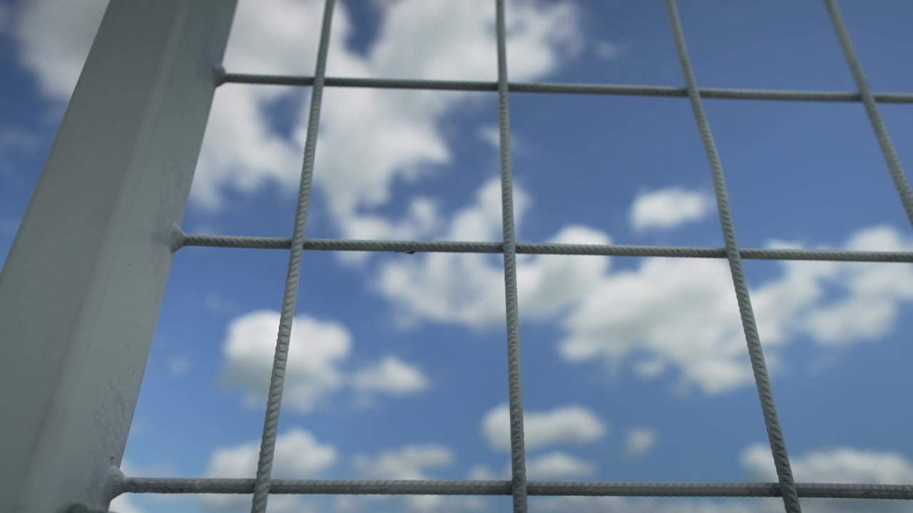 Recinzione contro il cielo blu, slow motion; 50 fps rallentato a 25