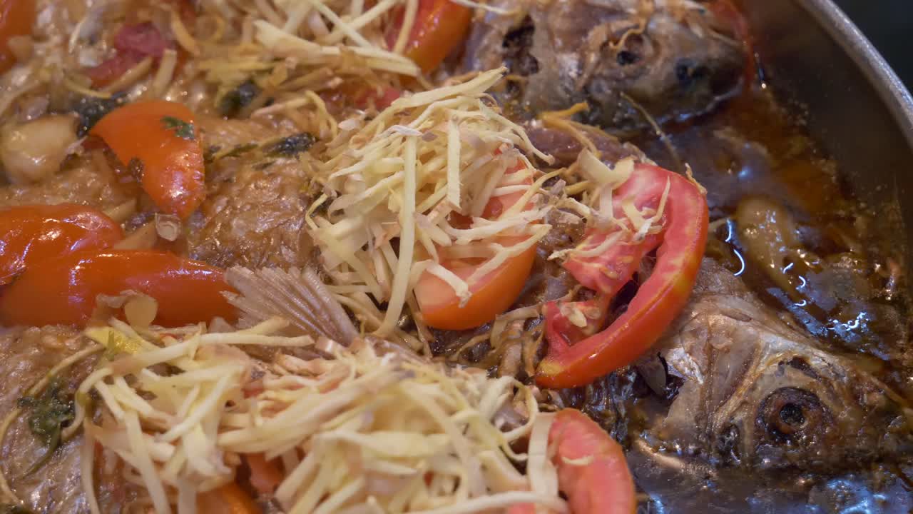 receta asiática de pescado frito cocinado en sopa de tomate con brotes documental en el mercado callejero de comida
