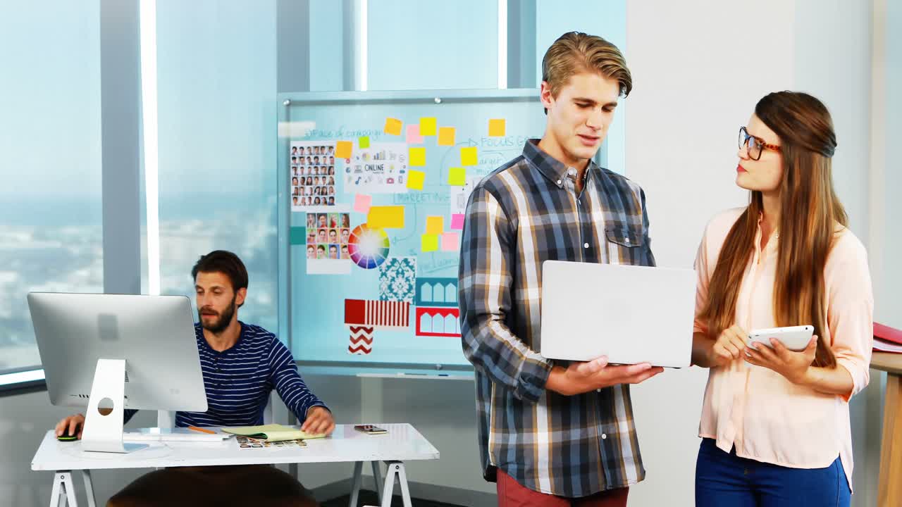 diseñadores gráficos discutiendo sobre una computadora portátil en la oficina