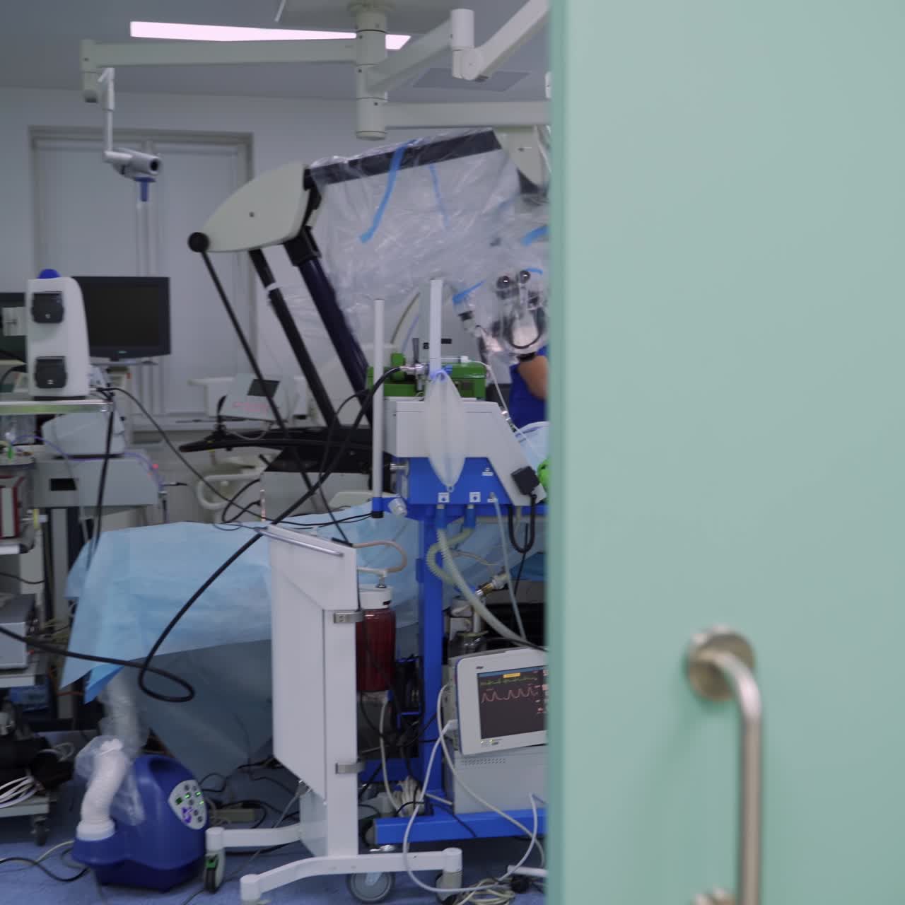 Modern technological equipment in operational room. Neurosurgical operation taking place in the ward. Camera moving from patient to the room entrance