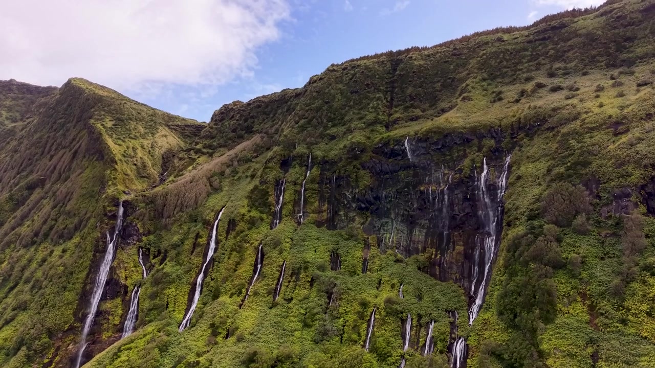 Veduta panoramica cinematografica di molteplici cascate che scendono attraverso un lussureggiante paesaggio vulcanico verde sull'isola di Flores, Azzorre, Portogallo.