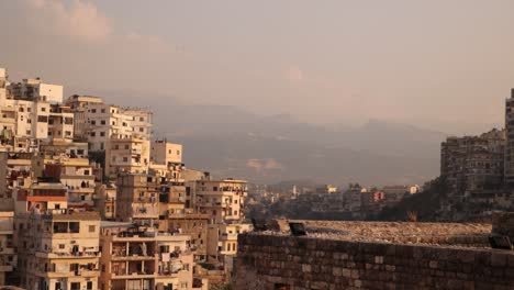 panning-shot-of-middle-eastern-homes-on-a-hill-with-mountains-in-the-distance-in-Tripoli,-Northern-Lebanon