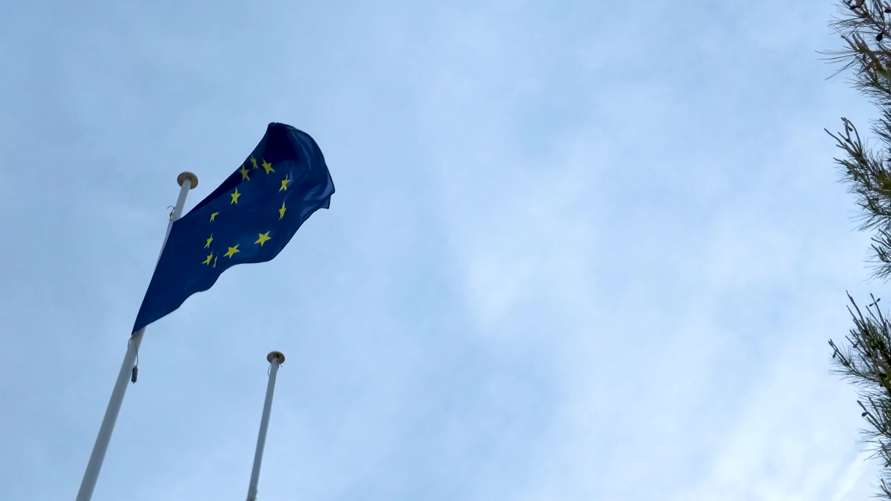 La bandiera dell'Unione Europea sventola in cima a un'alta asta contro un cielo diurno luminoso