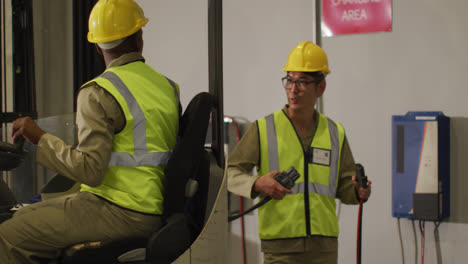 Diverse-male-workers-wearing-safety-suits-and-sitting-in-turret-truck-in-warehouse