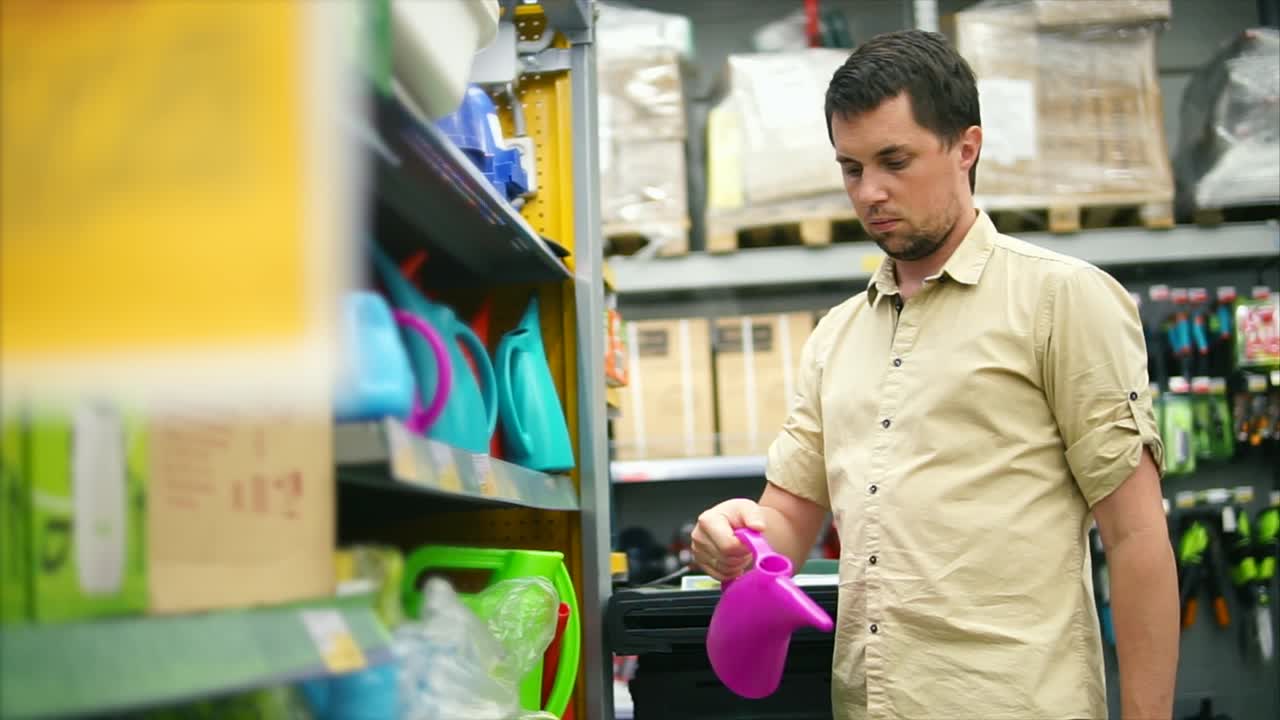 hombre comprando latas de riego en una tienda de suministros de jardín