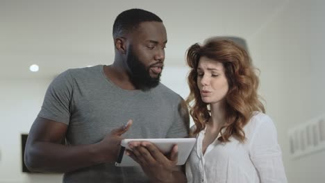 Young-couple-discussing-at-home-kitchen-together.-Black-man-showing-pictures