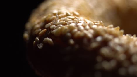 fresh bagels with sesame seeds in rotation. black background. extreme closeup.