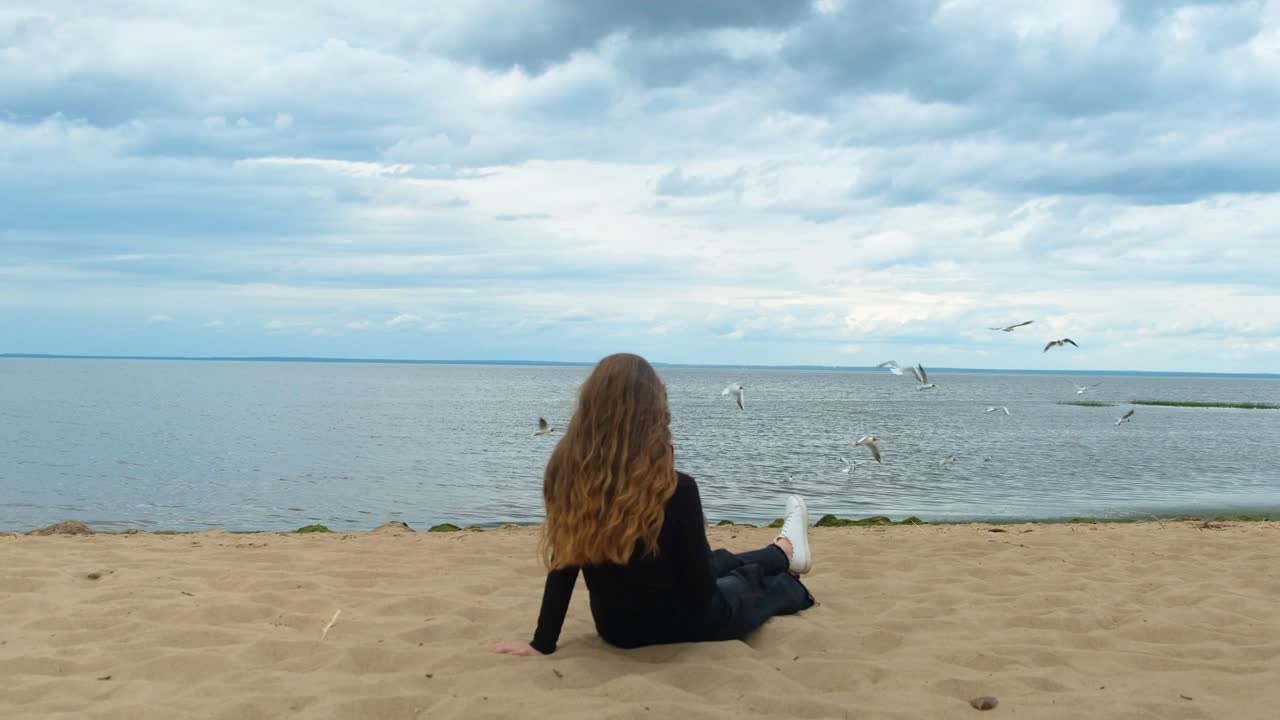 해변에 앉아 있는 소녀가 바다표범을 지켜보고 있다