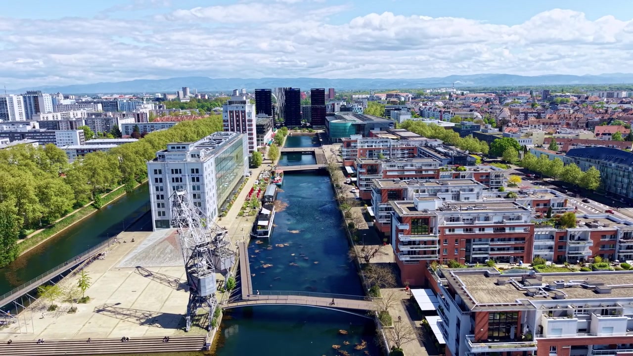 Bacino d'acqua con gru portuali e architettura moderna nel quartiere Presqu'ile Malraux a Strasburgo, Francia. Ripresa aerea laterale con drone