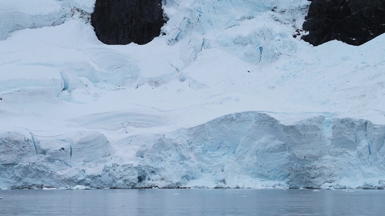 Glaciar y océano en la Antártida en la costa, paisaje invernal costero y de hielo, paisaje glacial helado con un gran glaciar junto al mar en la Península Antártica con una grieta y formaciones de hielo