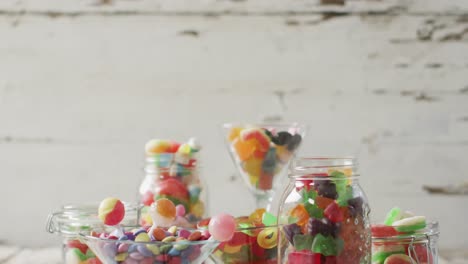 video of colourful various sweets in glass vessels on wooden table