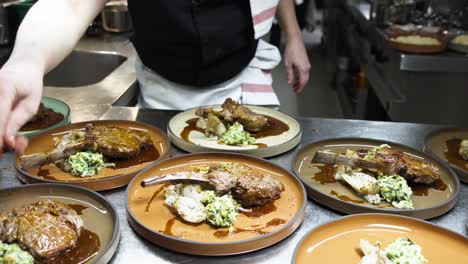 movimiento lento del chef añadido toque final adorno en tomahawk platos de filete en la cocina