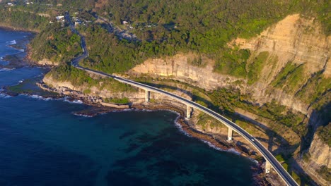 scenic australian road - the grand pacific drive with famous sea cliff bridge on vegetated rocky mountains in new south wales