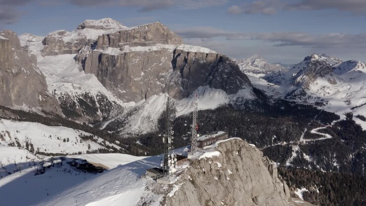 Cima alpina innevata con torri di telecomunicazione