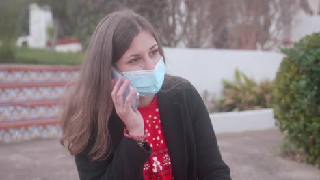 girl wearing a surgical mask and answering a phone call