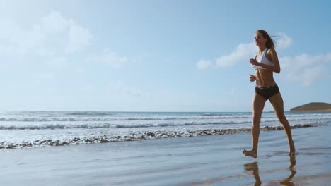 Healthy-woman-running-on-the-beach,-girl-doing-sport-outdoor,-happy-female-exercising,-freedom,-vacation,-fitness-and-heath-care-concept-with-copy-space-over-natural-background