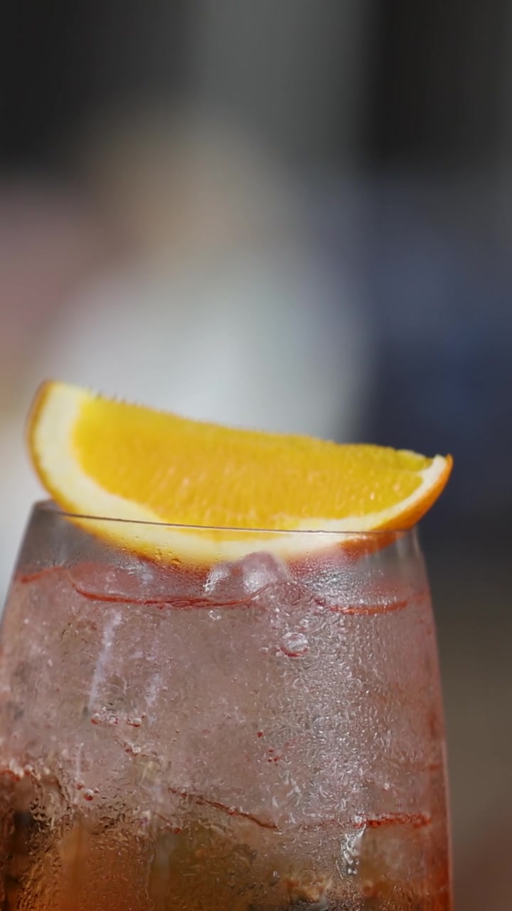 Un cocktail all'arancia ghiacciato in un bicchiere coperto di condensa, guarnito con una fetta di agrume fresco.