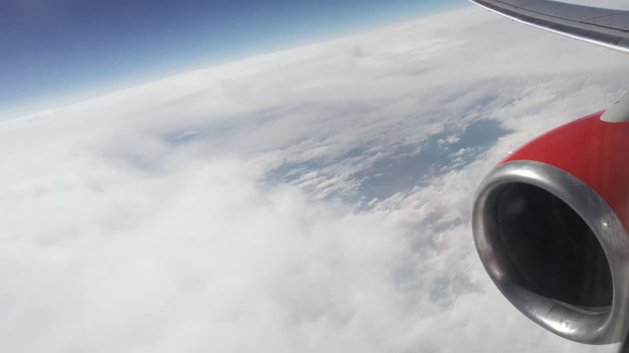 View of earth from a flying plane. Clouds, blue sky, plane engine