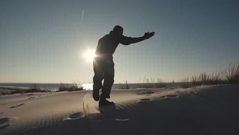 Male-dancer-in-silouhette-moves-on-top-of-sandy-hill,-steadicam-pulls-back