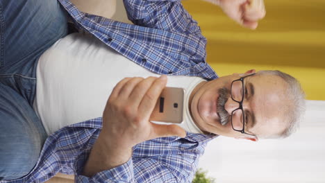 Vertikales-Video-Des-Alten-Mannes,-Der-Glücklich-Auf-Das-Telefon-Schaut.