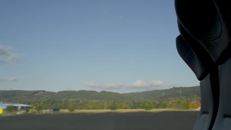 View-from-a-train-window-capturing-a-tranquil-rural-landscape-with-clear-skies,-timelapse