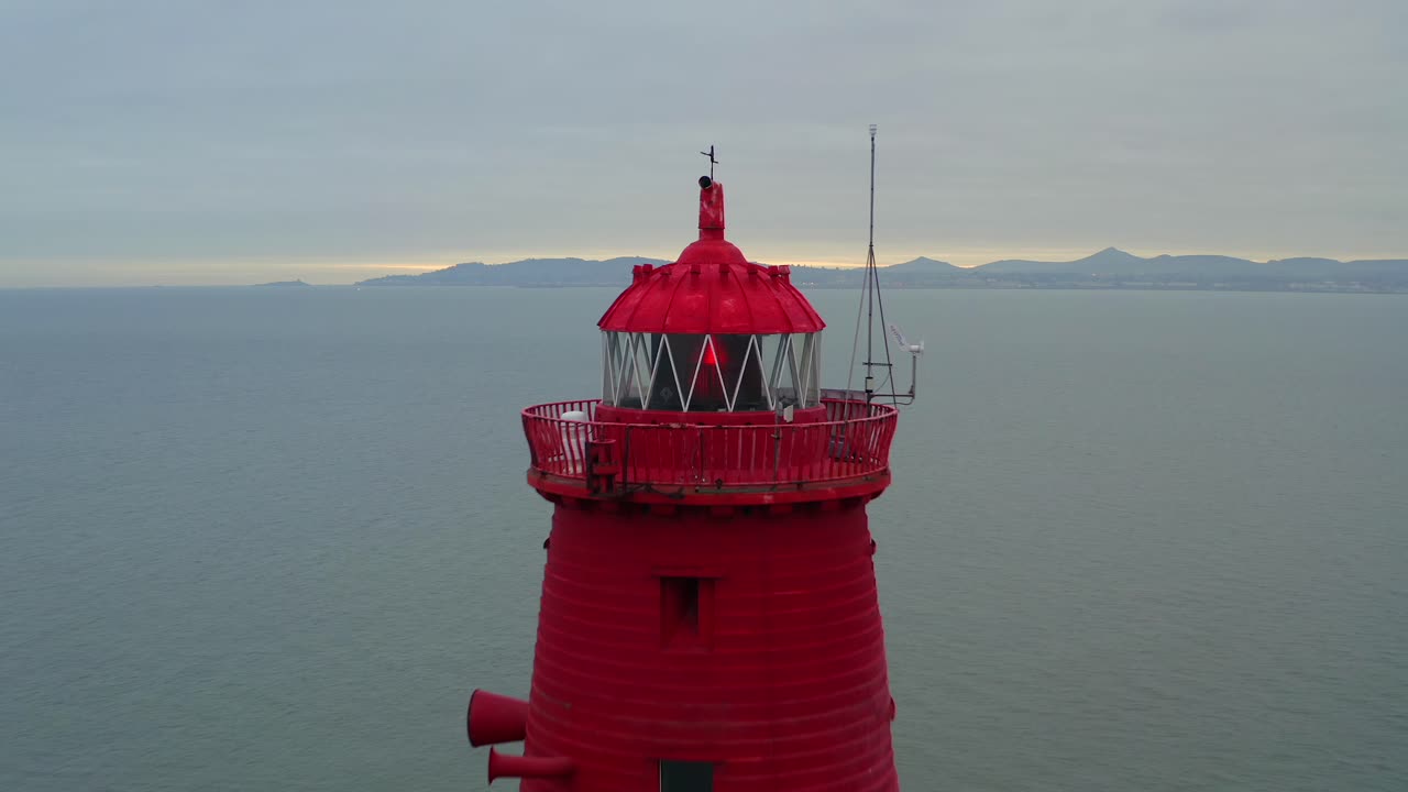 faro de poolbeg octogonal rojo al atardecer, dolly aéreo inverso