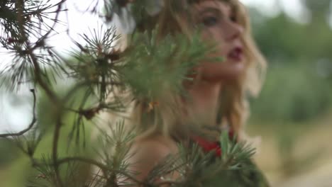 attractive young woman walking behind tree branches in green forest