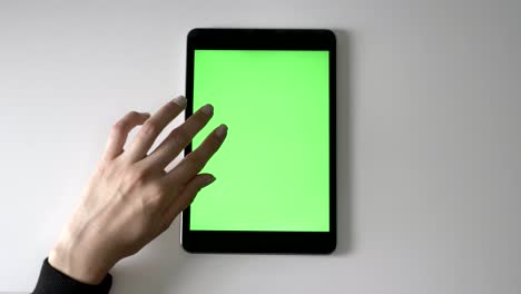 female hand scrolling on tablet. green screen, chromakey concept, top shot 60 fps