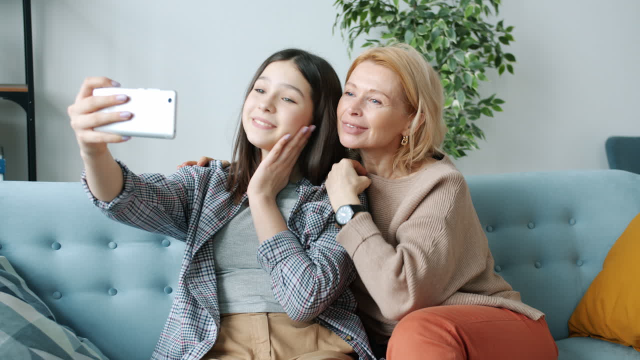 Mother and daughter taking a selfie on the couch.