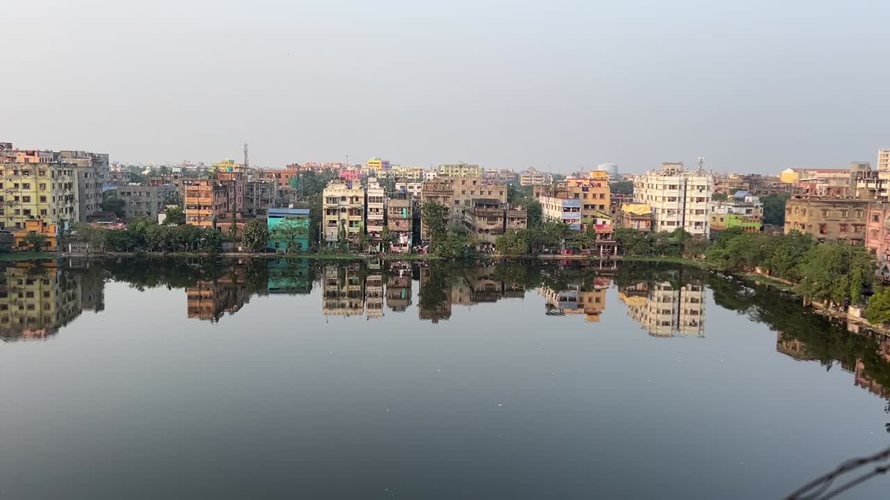 Vista diurna di un gruppo di edifici accanto a uno stagno a Calcutta, India.