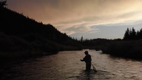 Ein-Einsamer-Fliegenfischer-Wirft-Seine-Rute-Mitten-Im-Fluss-Aus,-Wenn-Sich-Die-Dämmerung-Und-Die-Wolken-Nähern