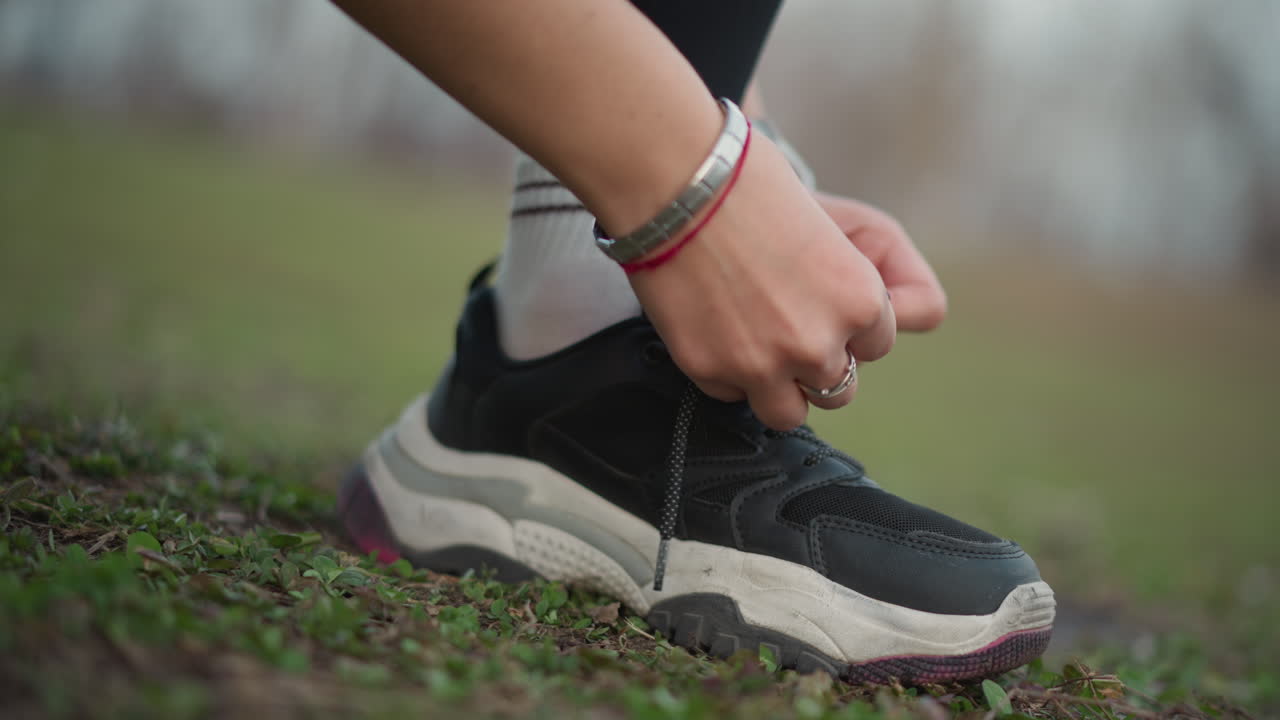Closeup Of Hiker Securing Sneaker Laces, Detailed Shot Of Athlete Fastening Trail Running Shoes Carefully, Close View Of Hiker Adjusting Shoelaces On Rugged Outdoor Trail Before Run