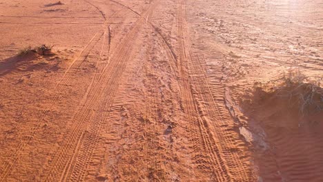 Vista-Trasera-De-Los-Senderos-De-Las-Ruedas-De-Un-Camión-4wd-Conduciendo-A-Través-De-La-Arena-Roja-Del-Desierto-De-Wadi-Rum-En-Jordania