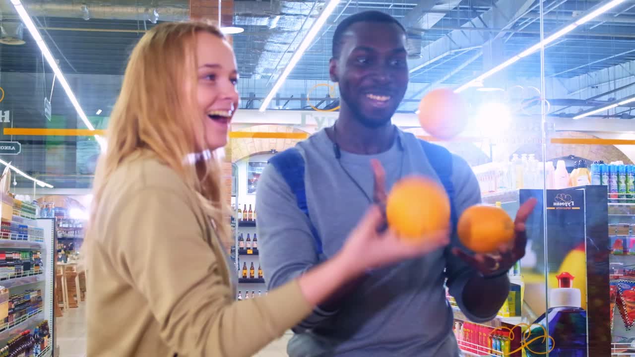 Momenti gioiosi di amicizia: Due amici che giocolano giocosamente con le arance in un vivace supermercato, condividendo risate e divertimento nella loro avventura quotidiana.