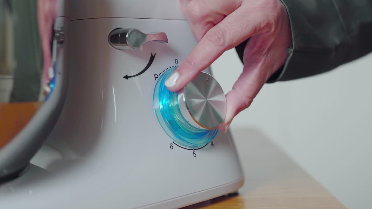 Hands turning speed dial on food processor kitchen appliance. Closeup