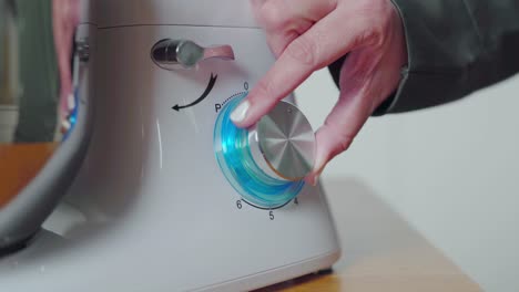 hands turning speed dial on food processor kitchen appliance. closeup